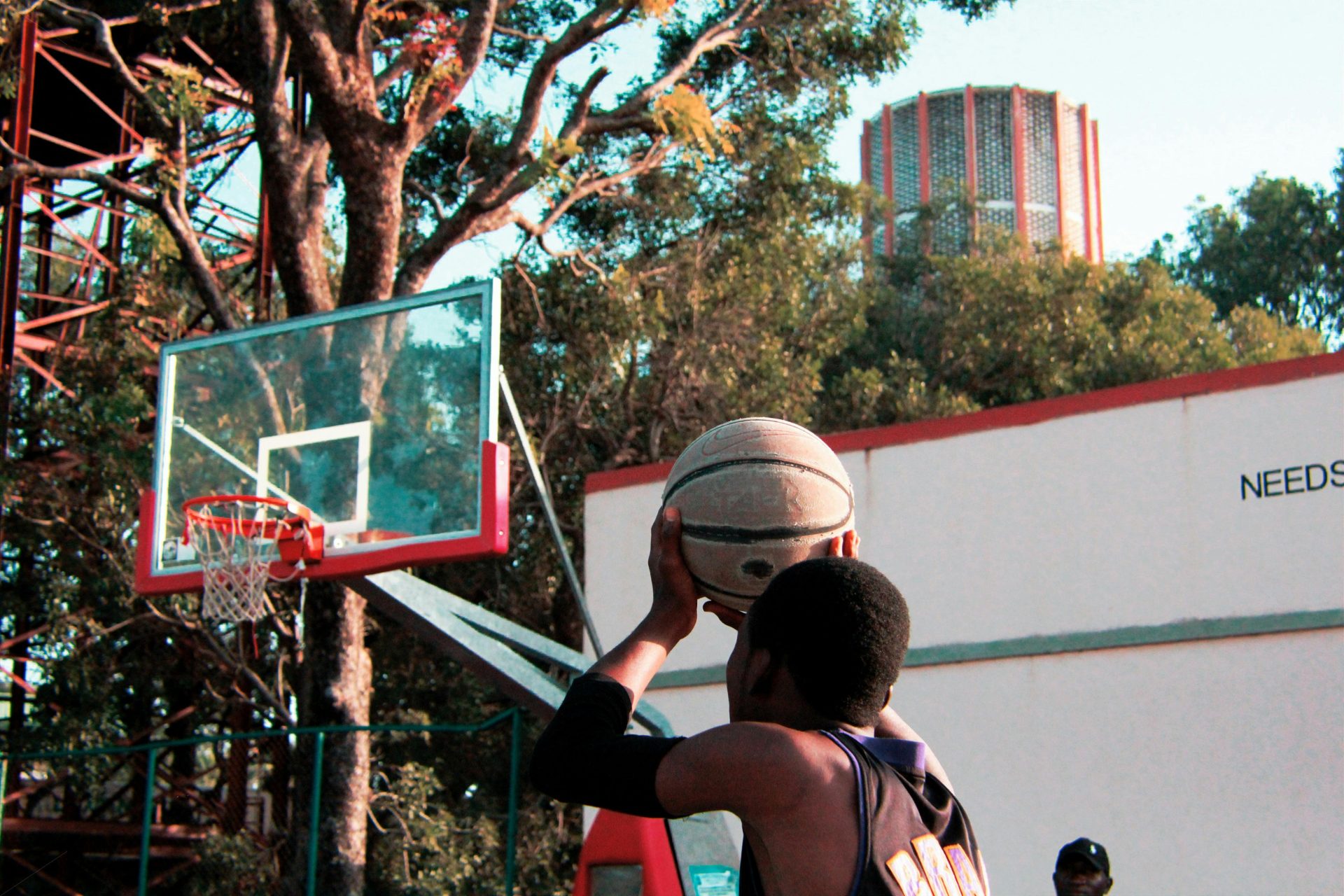 Un joven jugador aspira a anotar en una cancha de baloncesto al aire libre, capturando la esencia del deporte y la determinación.