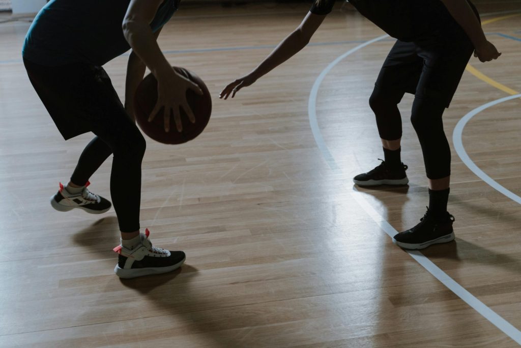 Silueta de dos jugadores disputando un partido de baloncesto en una cancha cubierta.